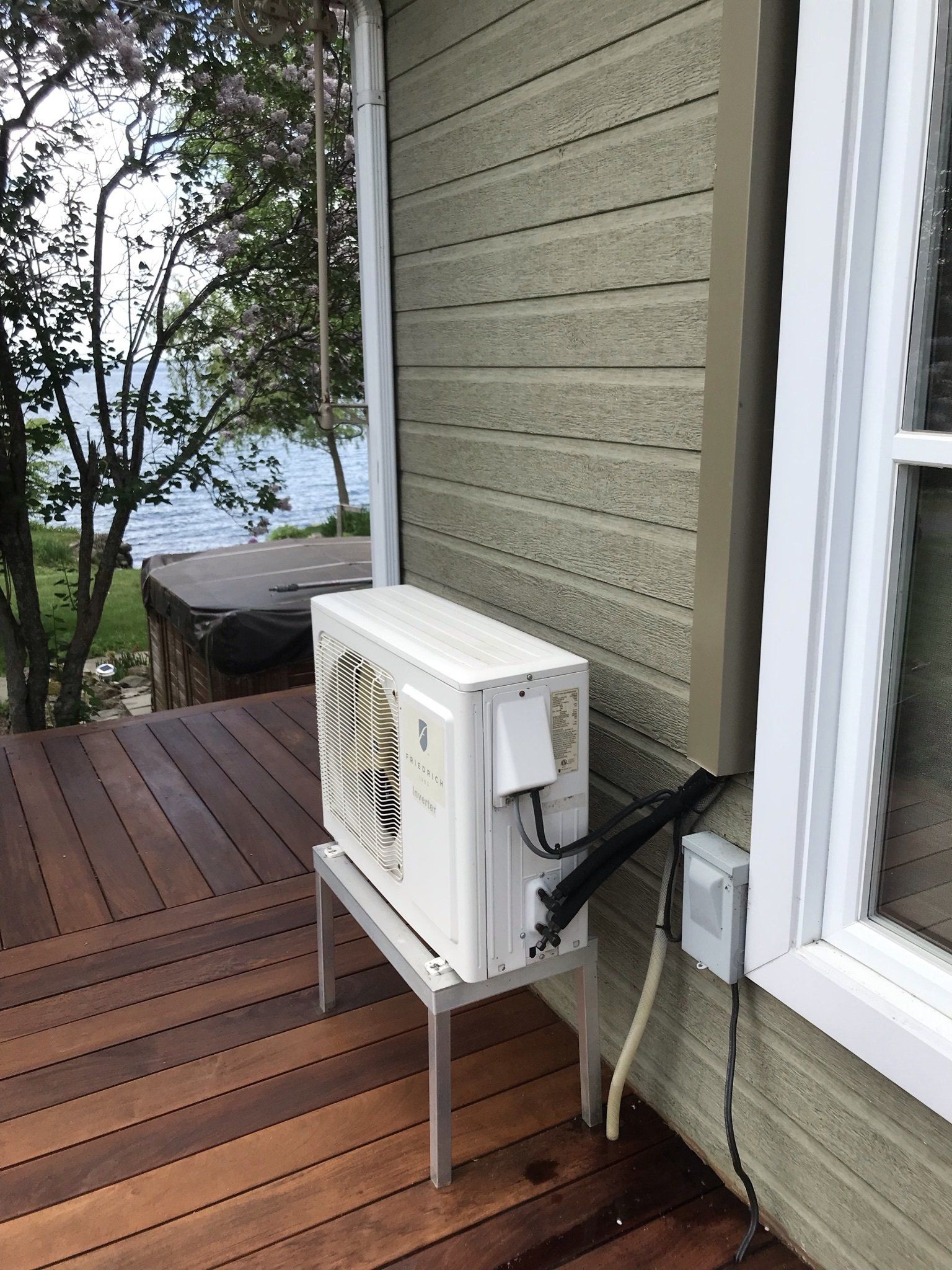 Unité de climatisation extérieure sur une terrasse à côté d'un bâtiment, avec vue sur l'eau.