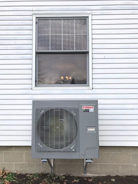 Mur extérieur avec fenêtre au-dessus du climatiseur gris.