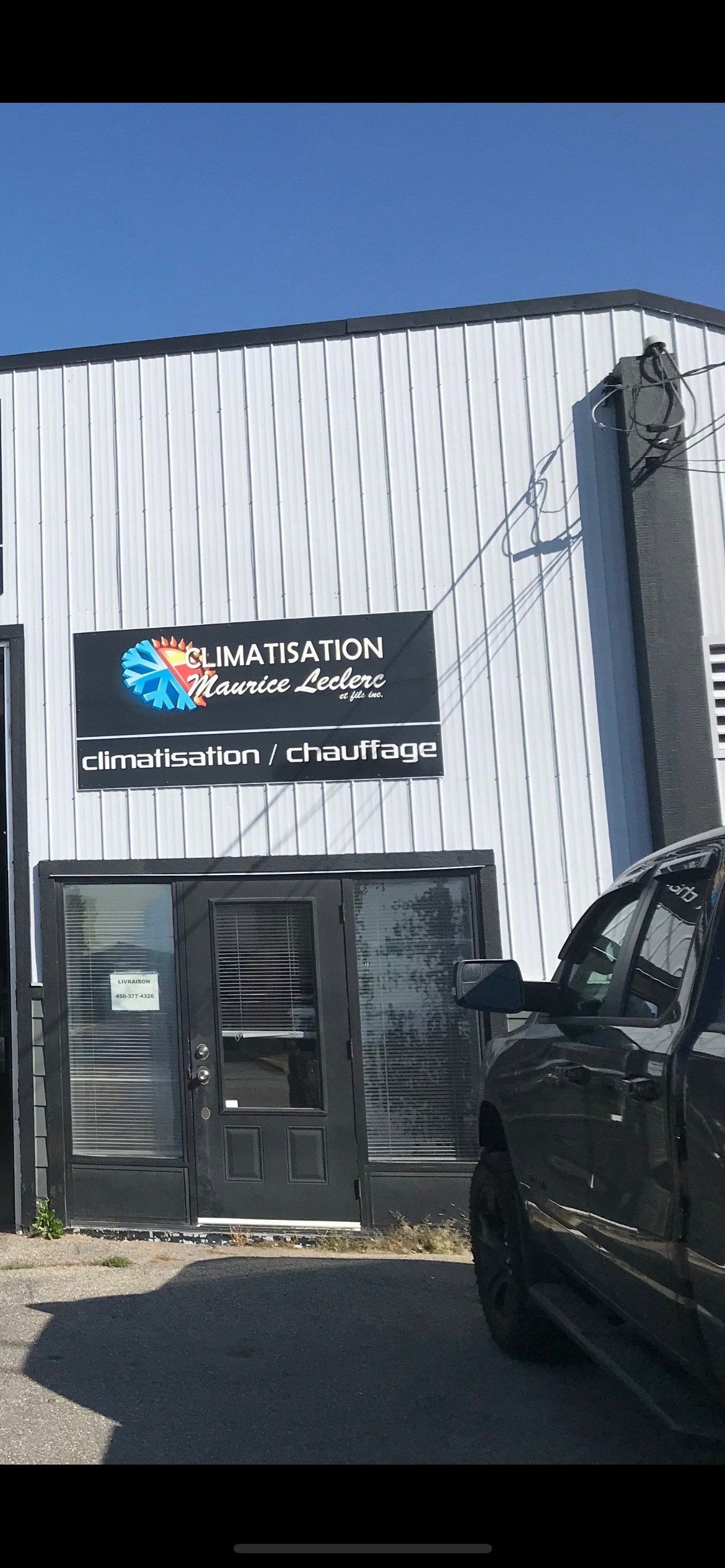 Extérieur d'un bâtiment avec une enseigne « Elevation Neuro Dynamics ». Porte noire, camion garé à l'extérieur par une journée ensoleillée.