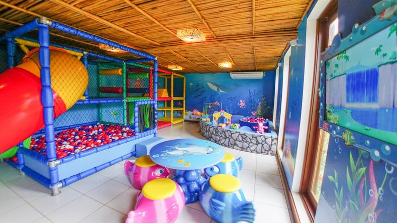 Piscina e banheiras de hidromassagem perto da praia com palmeiras e telhados de palha.