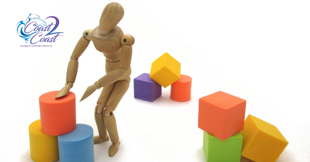 A Wooden Mannequin Is Standing Next to A Pile of Colourful Boxes — Coast 2 Coast Disability Support