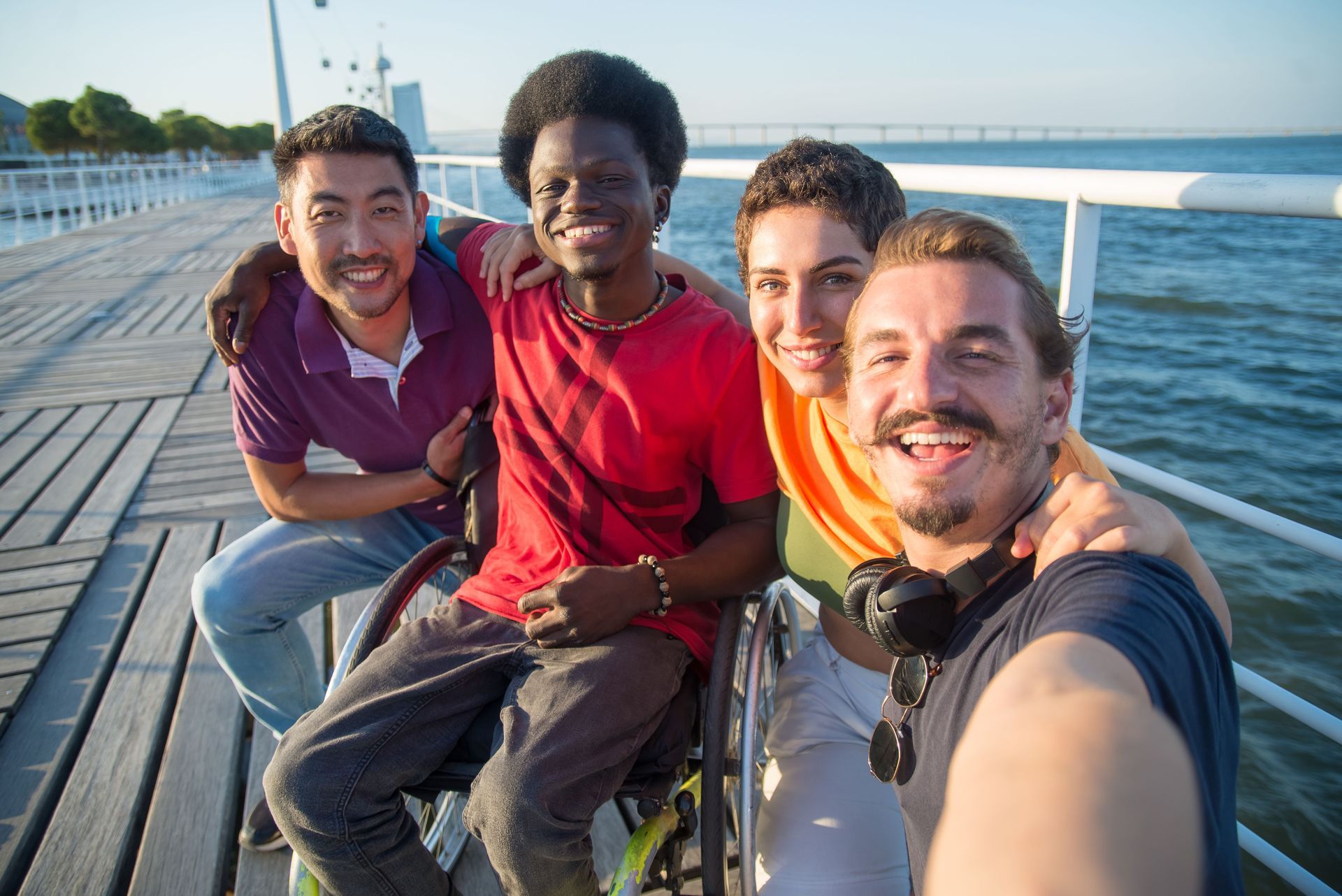 Four Friends Smiling on A Bridge at Sunset — Coast 2 Coast Disability Support Services in Taree, NSW