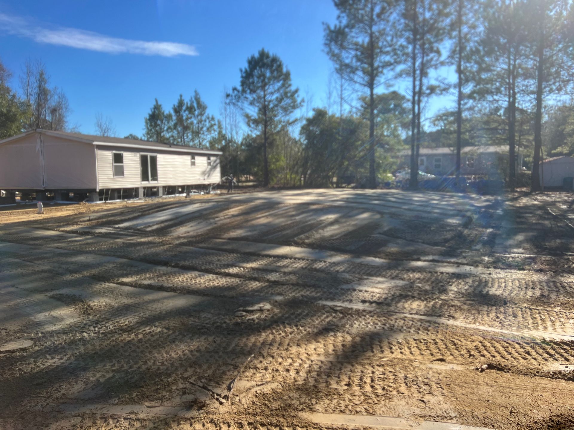 A mobile home is sitting in the middle of a dirt field.