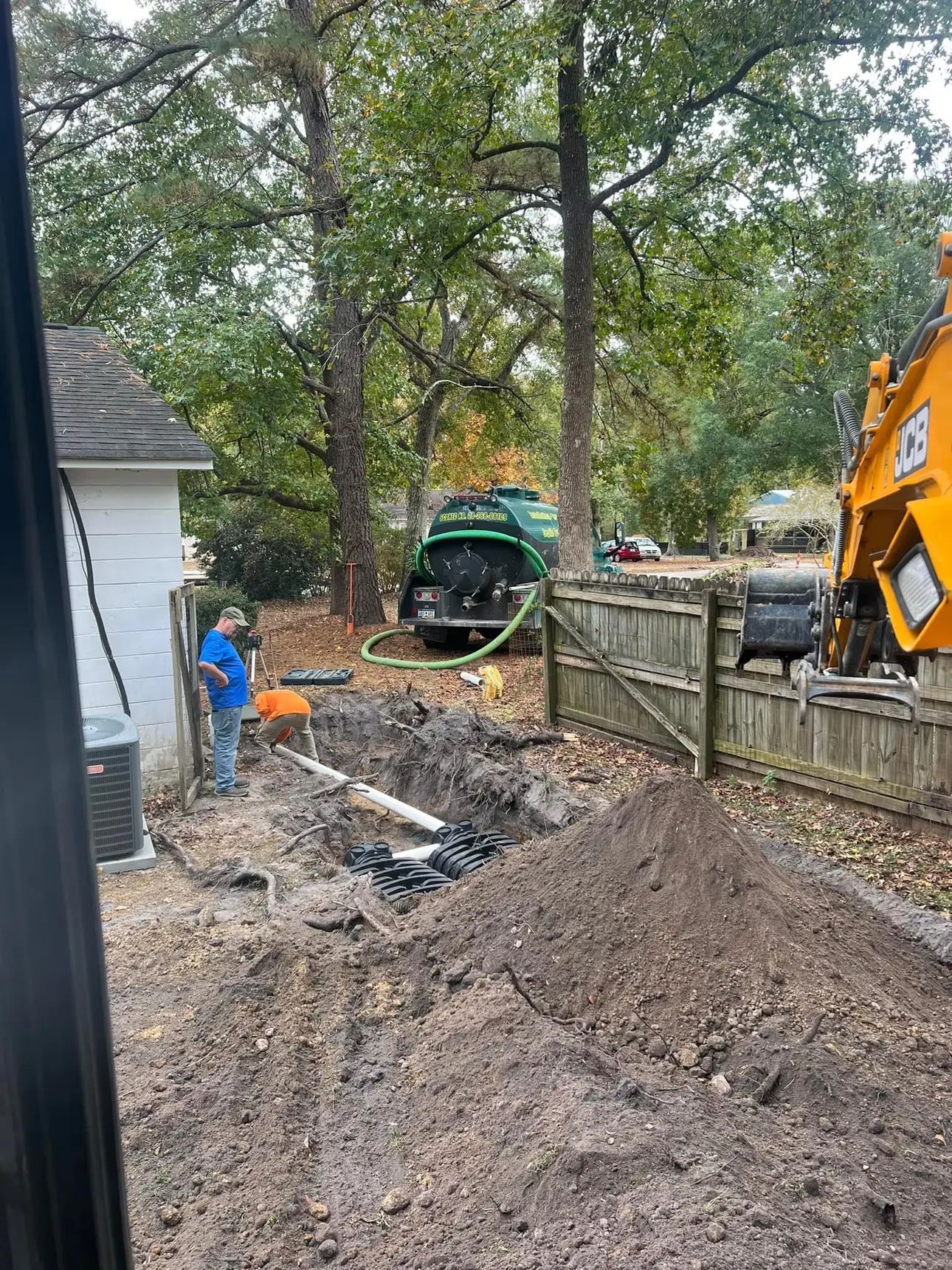 A man is standing next to a large pile of dirt in a yard.