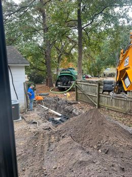A man is standing next to a large pile of dirt in a yard.