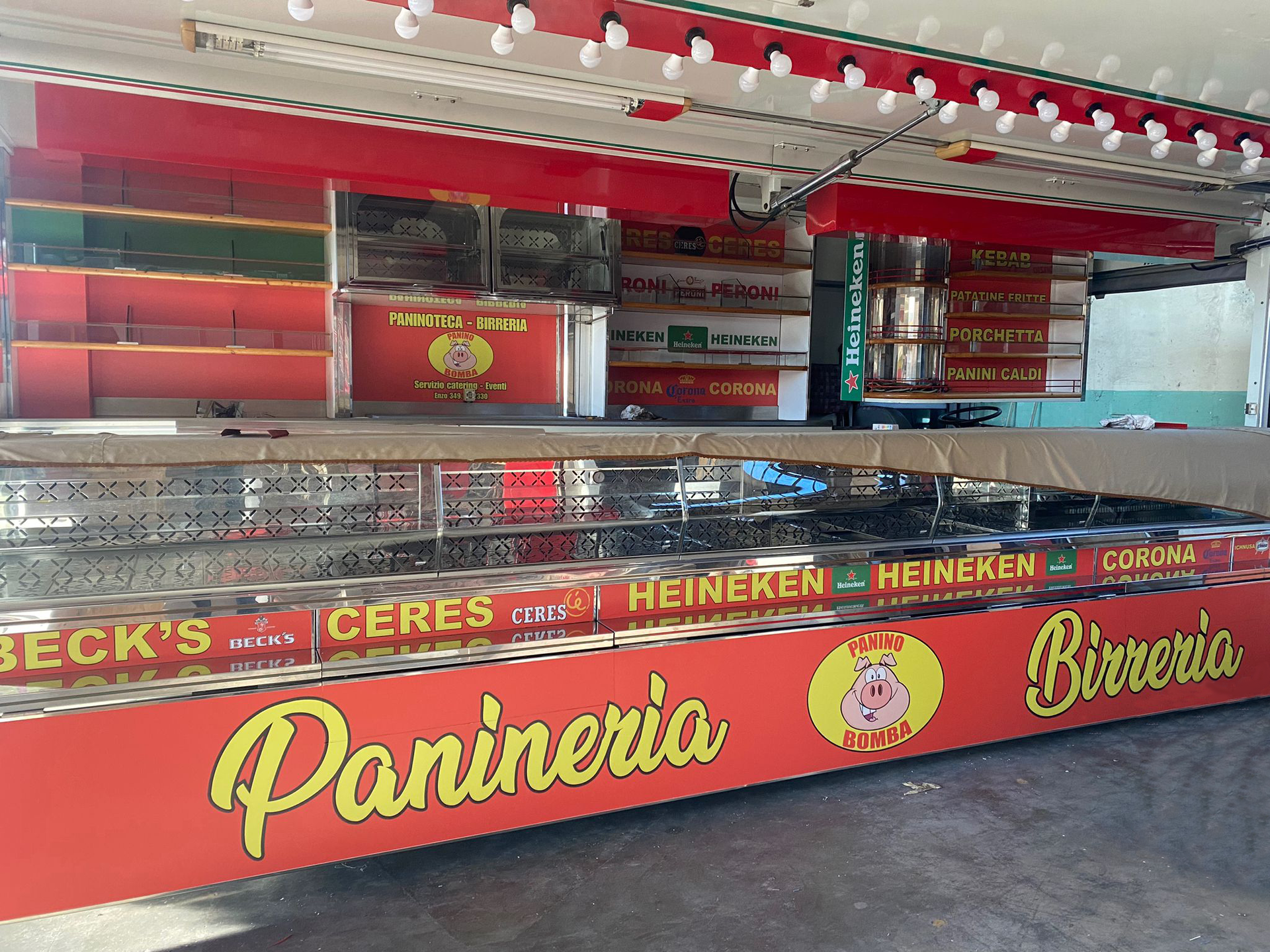 Un chiosco rosso che vende panini e birra, con le insegne