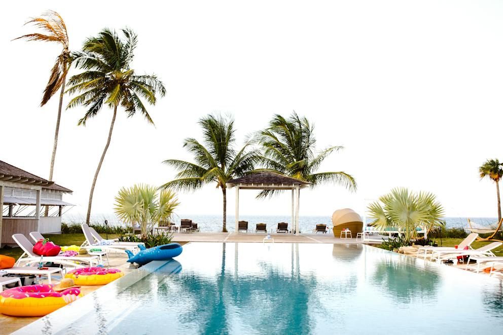 Palm-lined resort infinity pool with colorful loungers and ocean view