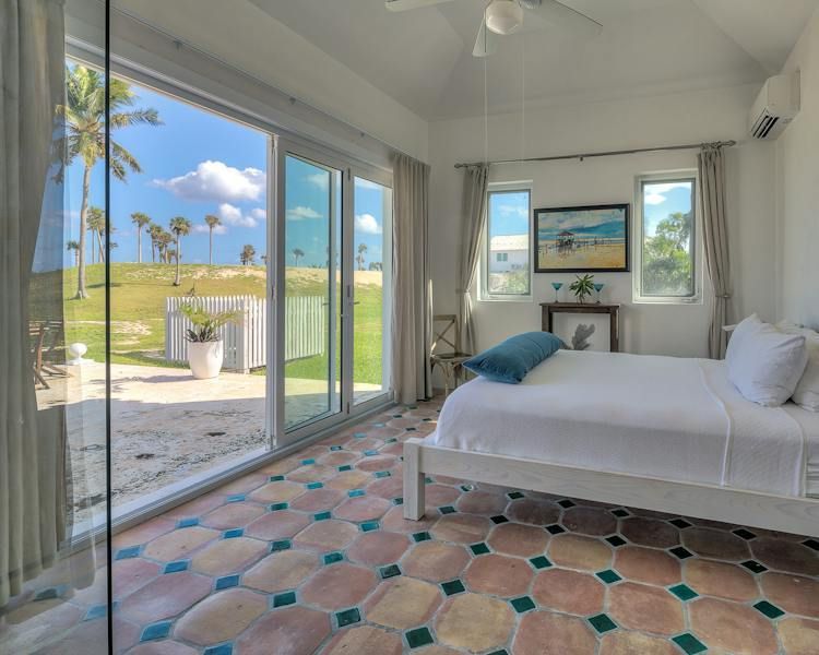 Bright bedroom with sliding glass doors, ocean view, and patterned tiled floor