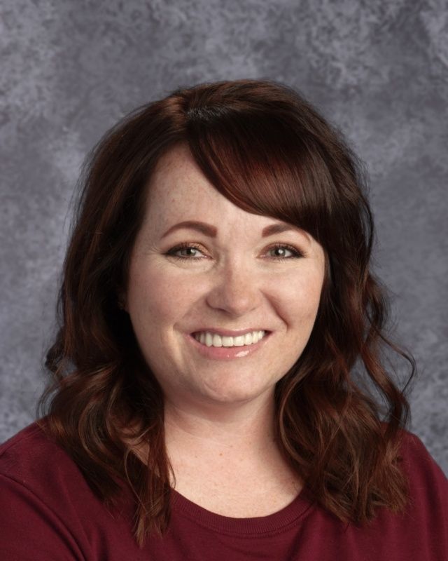 A woman in a red shirt is smiling for the camera.