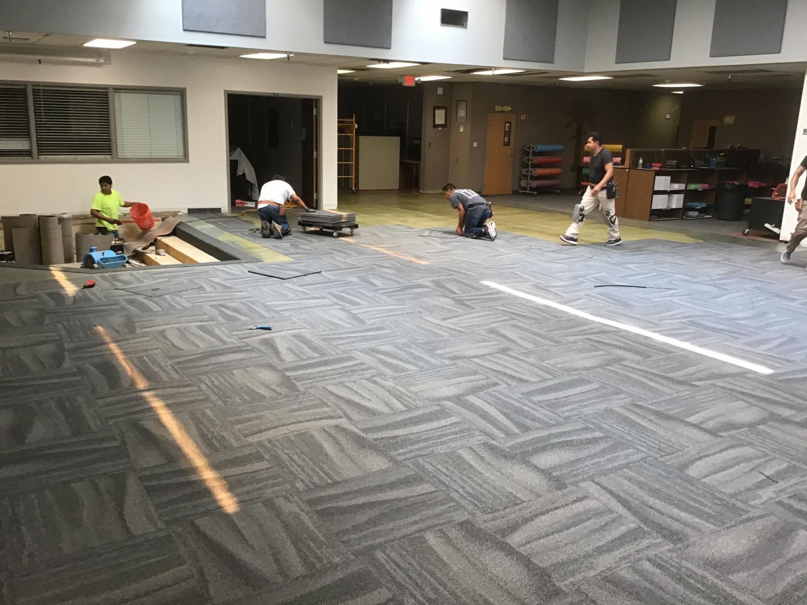 A group of people are working on a carpeted floor in a room.