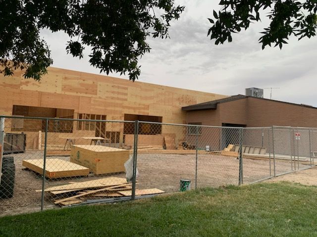 A building under construction is behind a chain link fence