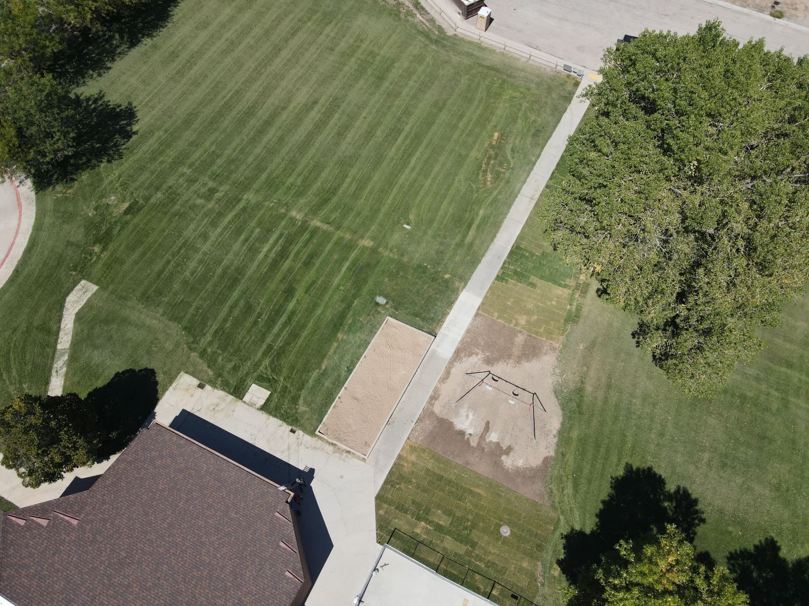 An aerial view of a lush green field with a house in the background
