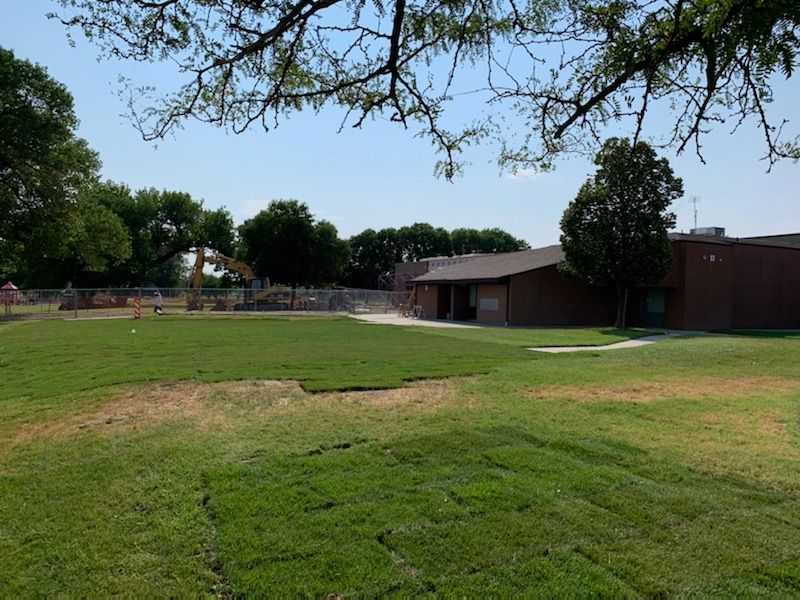 A large grassy field with a brick building in the background