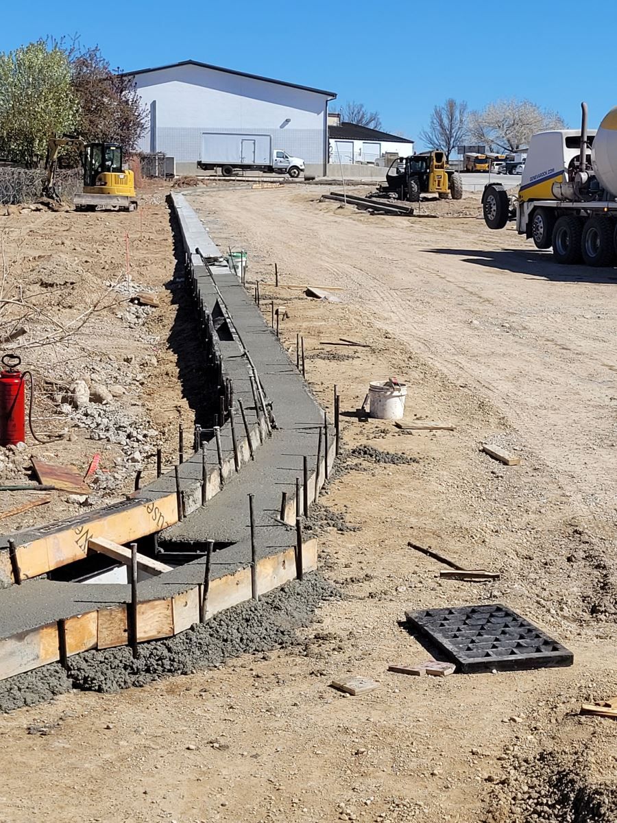 A concrete wall is being built in the middle of a dirt road.