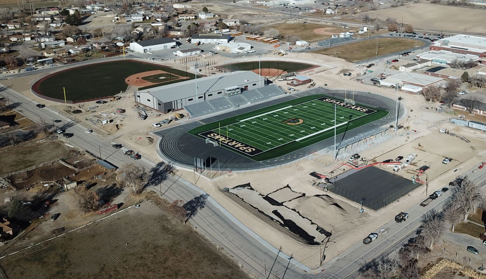 An aerial view of a football stadium with a baseball field in the background.