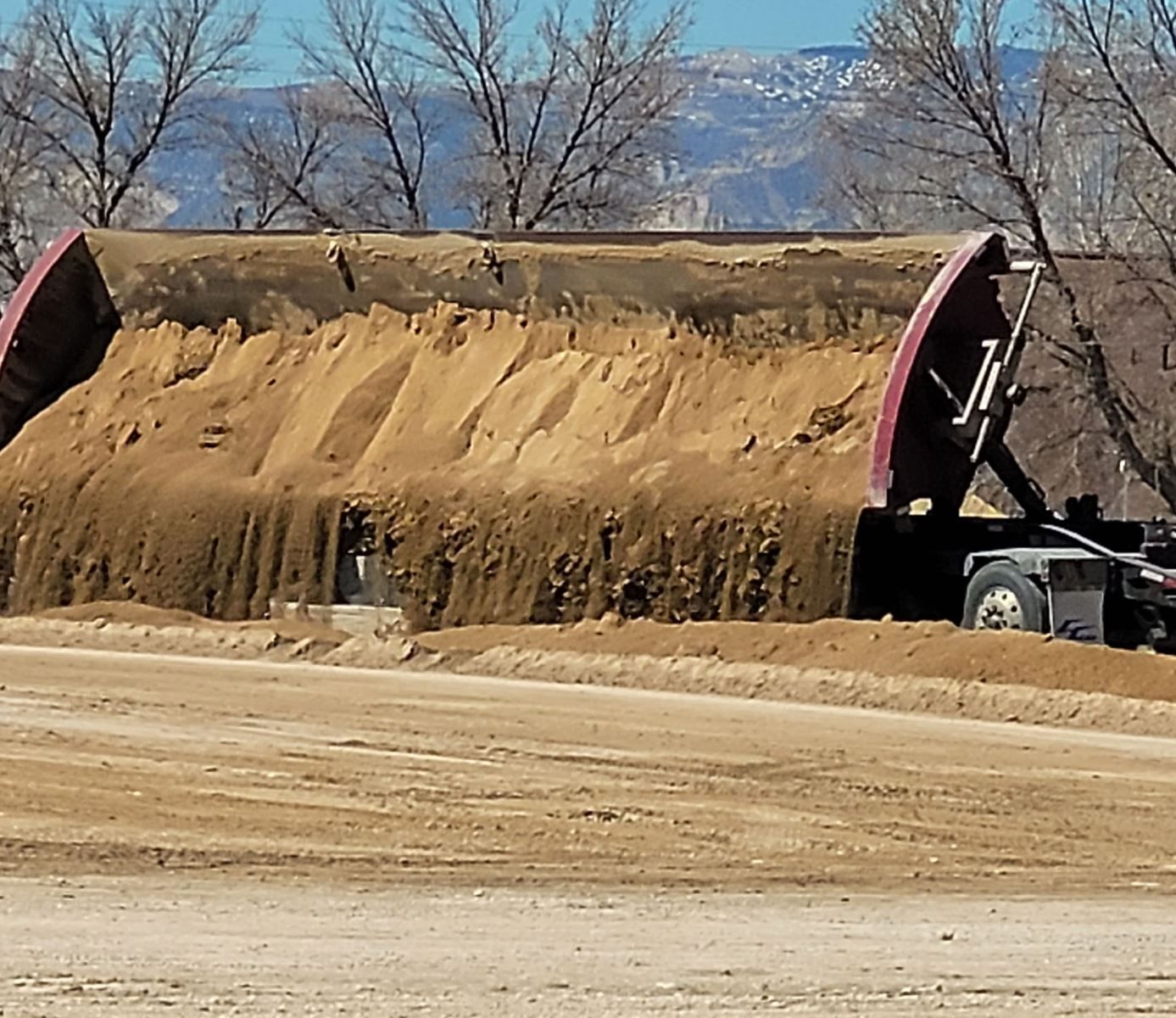A dump truck is carrying a large pile of dirt