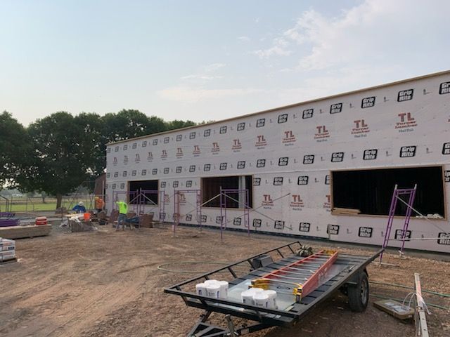 A trailer with a ladder on it is parked in front of a building under construction