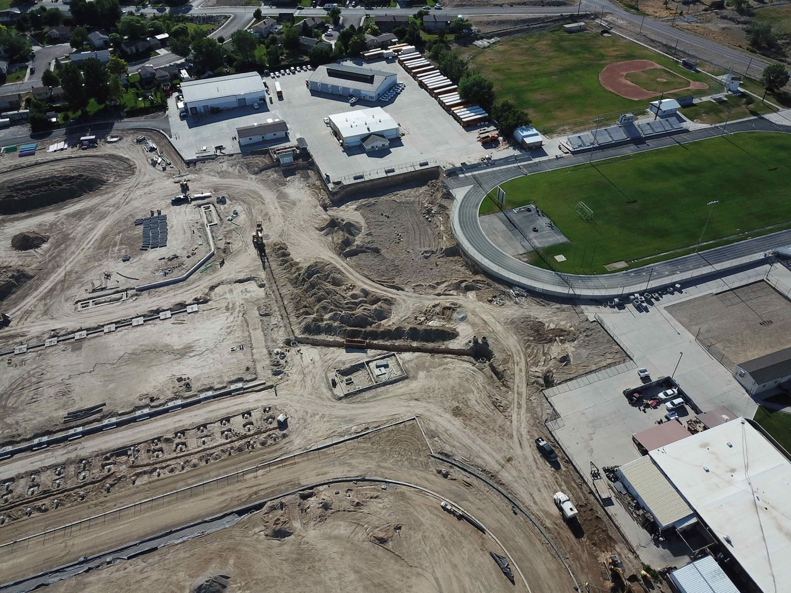 An aerial view of a construction site with a baseball field in the background.