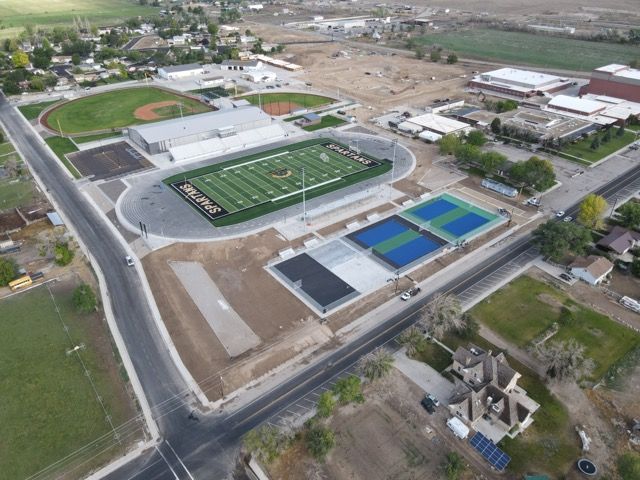 An aerial view of a school with a football field and tennis courts.
