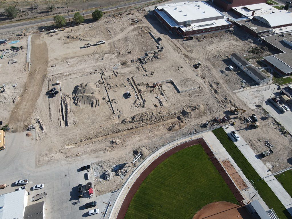 An aerial view of a construction site with a baseball field in the foreground