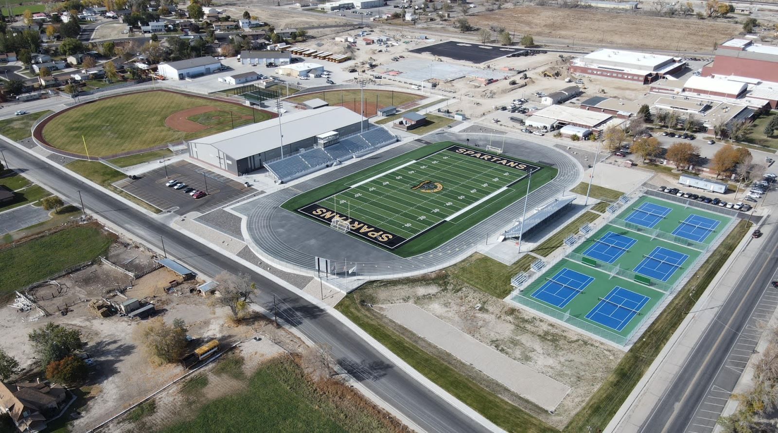 An aerial view of a stadium with tennis courts and a football field.