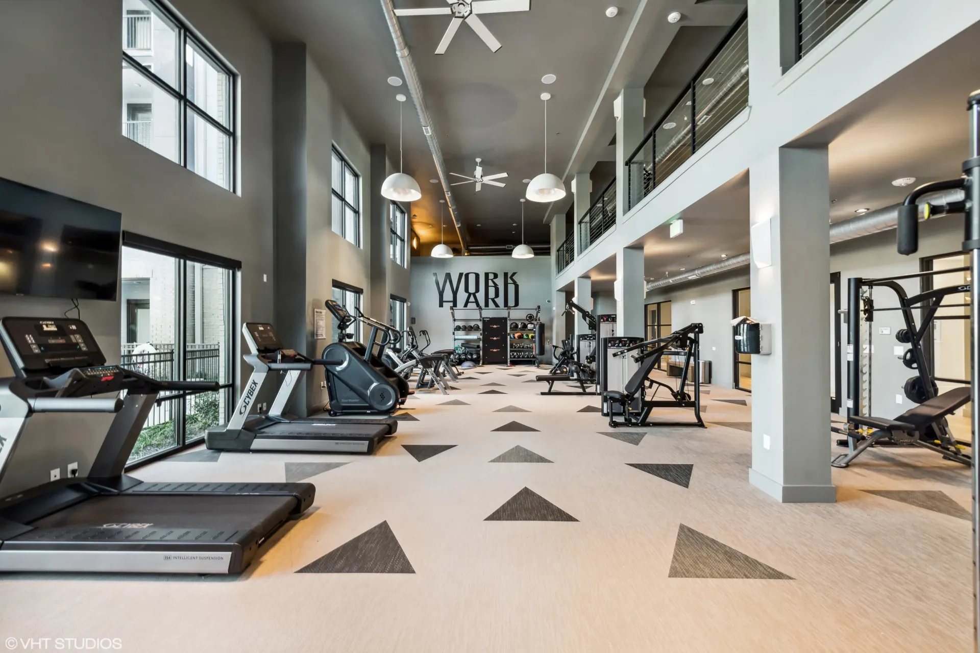 Interior view of a modern apartment gym with cardio and weight machines.