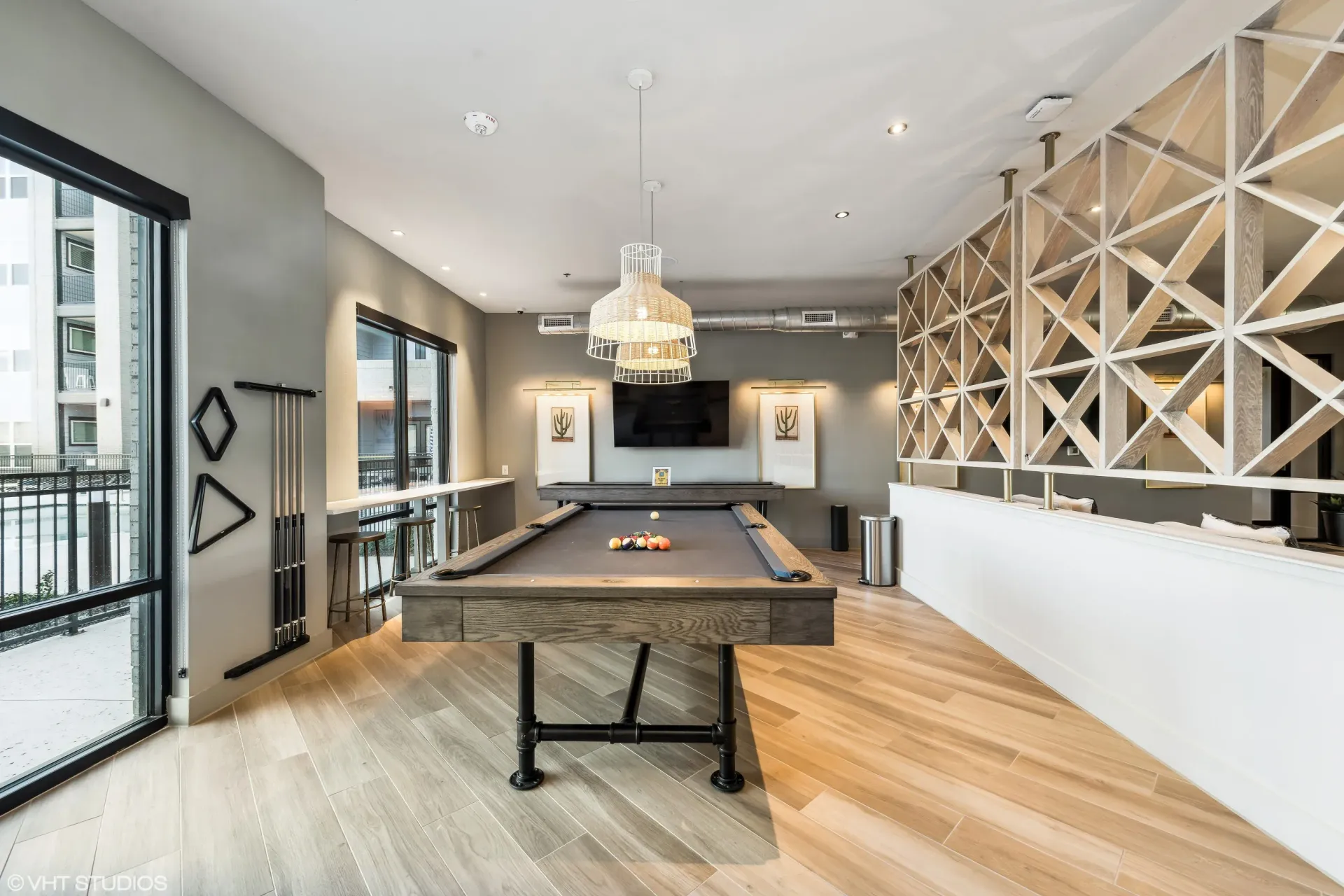 Modern apartment amenity room with a pool table, bar seating, and geometric lattice divider.