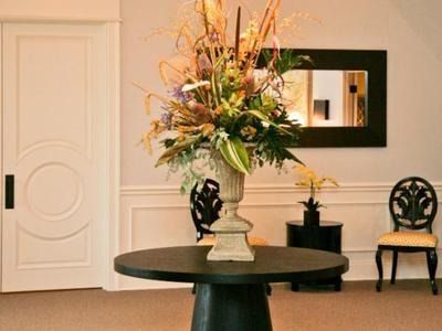 Elegant lobby with a round table, floral arrangement, mirror, and two chairs against a light wall