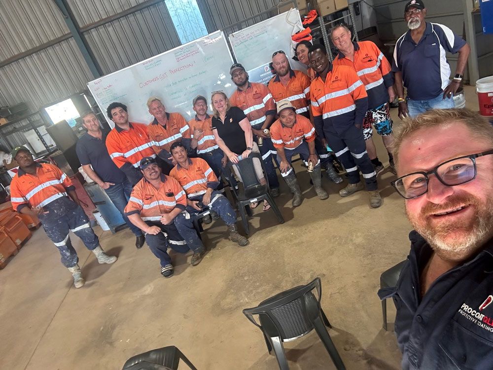 A Group Of  Procoat Workers Are Posing For A Picture In A Warehouse — Procoat QLD in Ryan, QLD