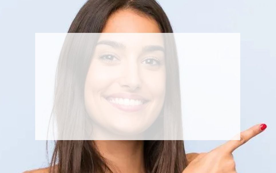 A woman is holding a white card in front of her face and pointing at it.