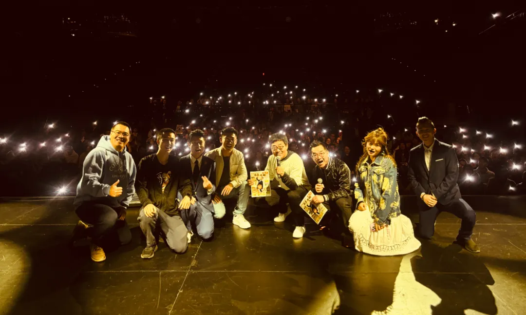A group of people are posing for a picture on a stage at night.
