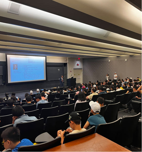 A large auditorium filled with people watching a presentation