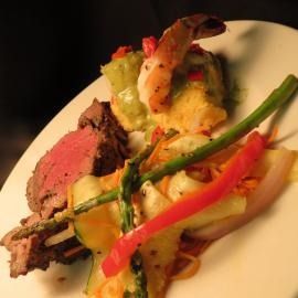 Plated steak with grilled vegetables and colorful peppers on a white dish