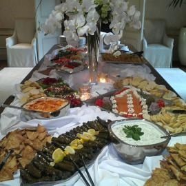 Buffet table with assorted dishes, floral centerpiece, and white chair covers in a decorated dining room