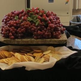 Large bowl of red grapes on a table with assorted crackers and bread in the foreground