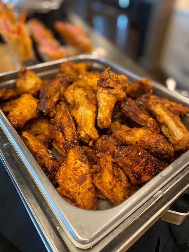 Tray of crispy seasoned chicken wings at a buffet counter