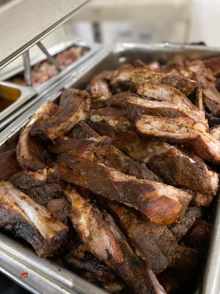 Tray of grilled meat ribs in a stainless steel buffet pan
