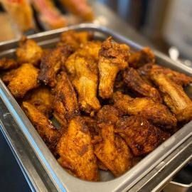 Tray of crispy fried chicken wings in a stainless-steel buffet pan