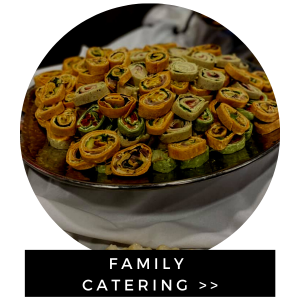 Platter of assorted rolled appetizers with “FAMILY CATERING” banner below