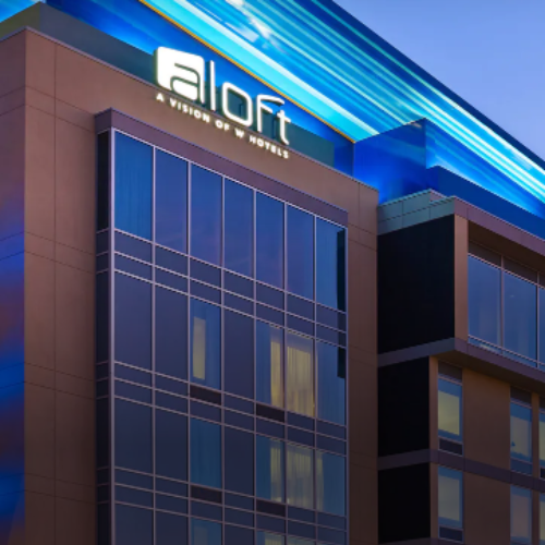 Aloft hotel building at dusk with blue-lit facade and reflective glass windows