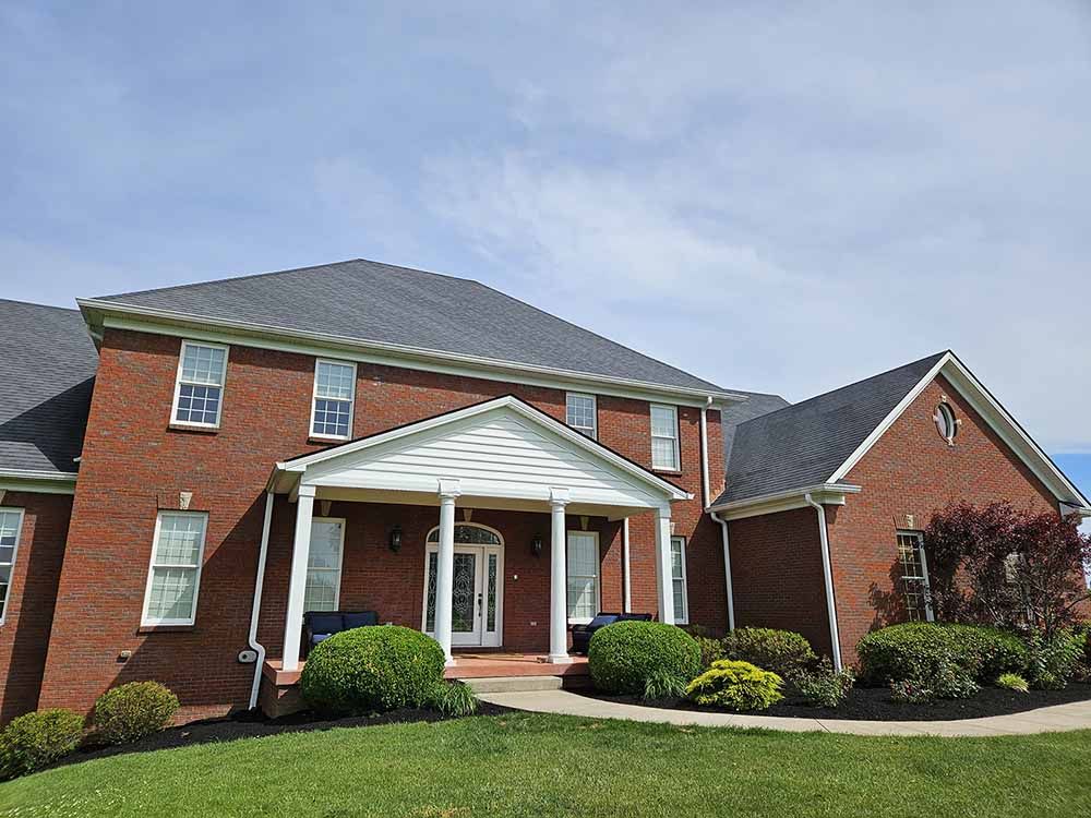A large brick house with a porch and a gray roof.