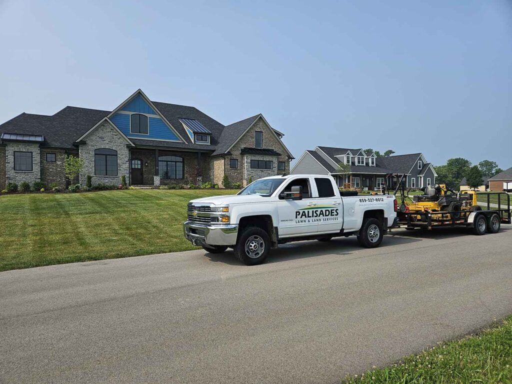 A white truck is driving down a road next to a house.