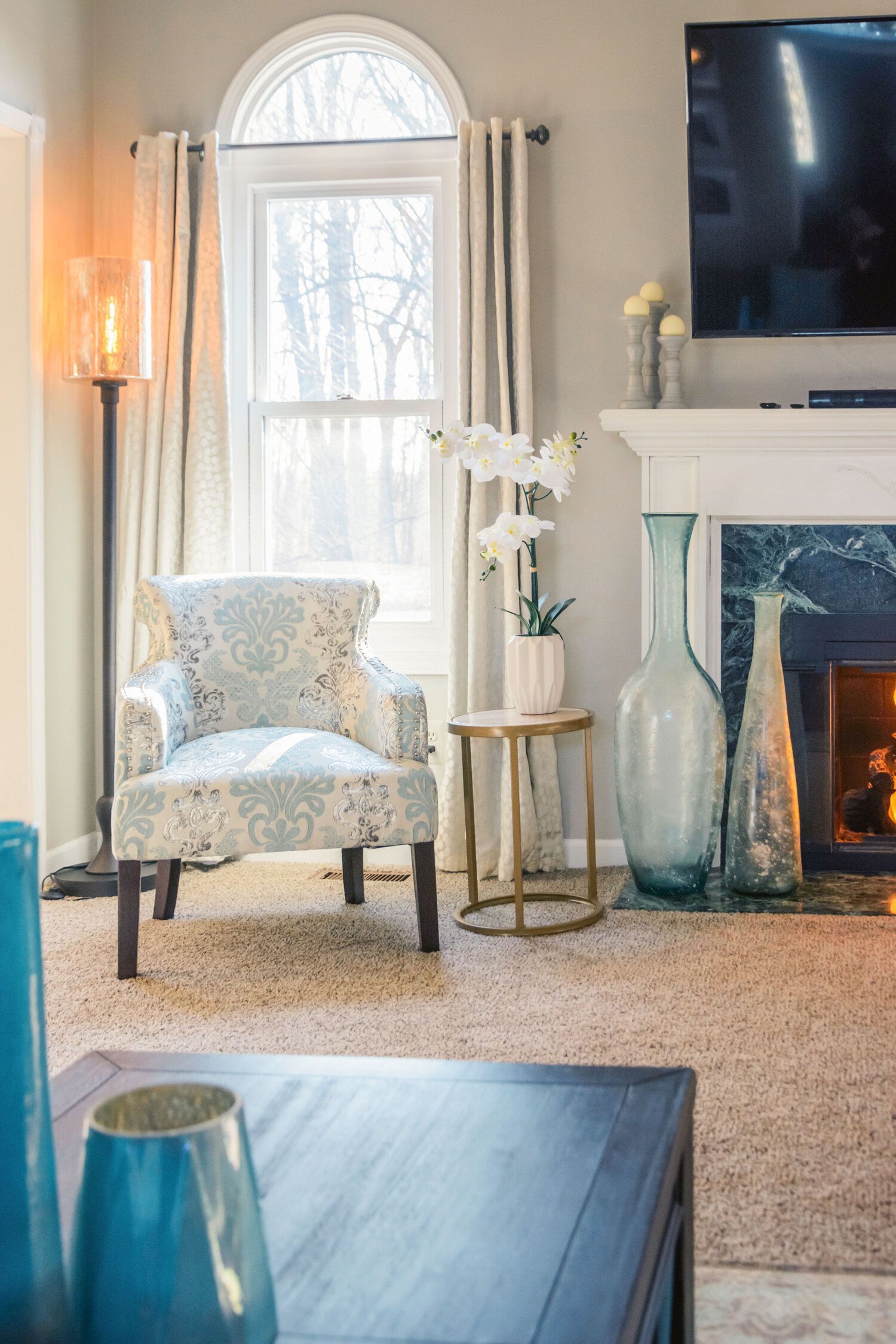 A living room with a fireplace , chair , table and television.