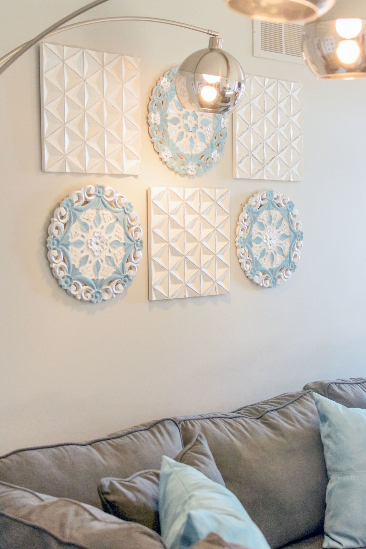 A living room with a couch , pillows , and plates on the wall.