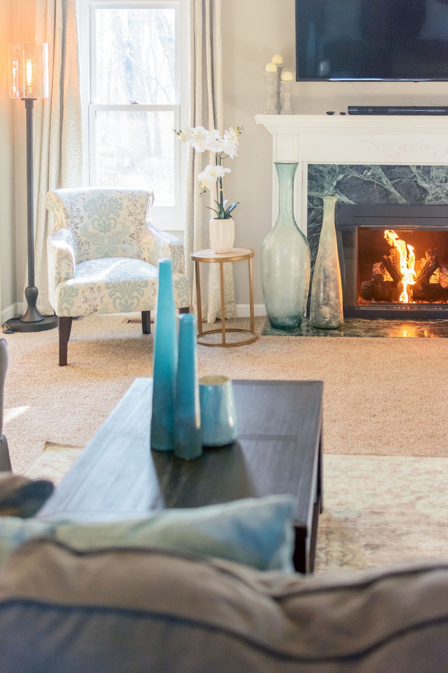 A living room with a fireplace , couch , chair and television.
