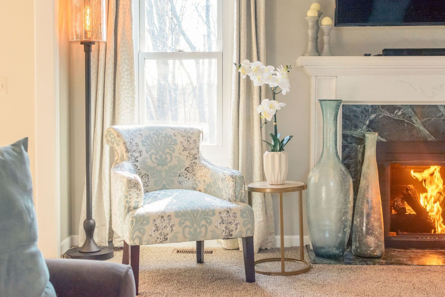 A living room with a fireplace , chair , table and television.