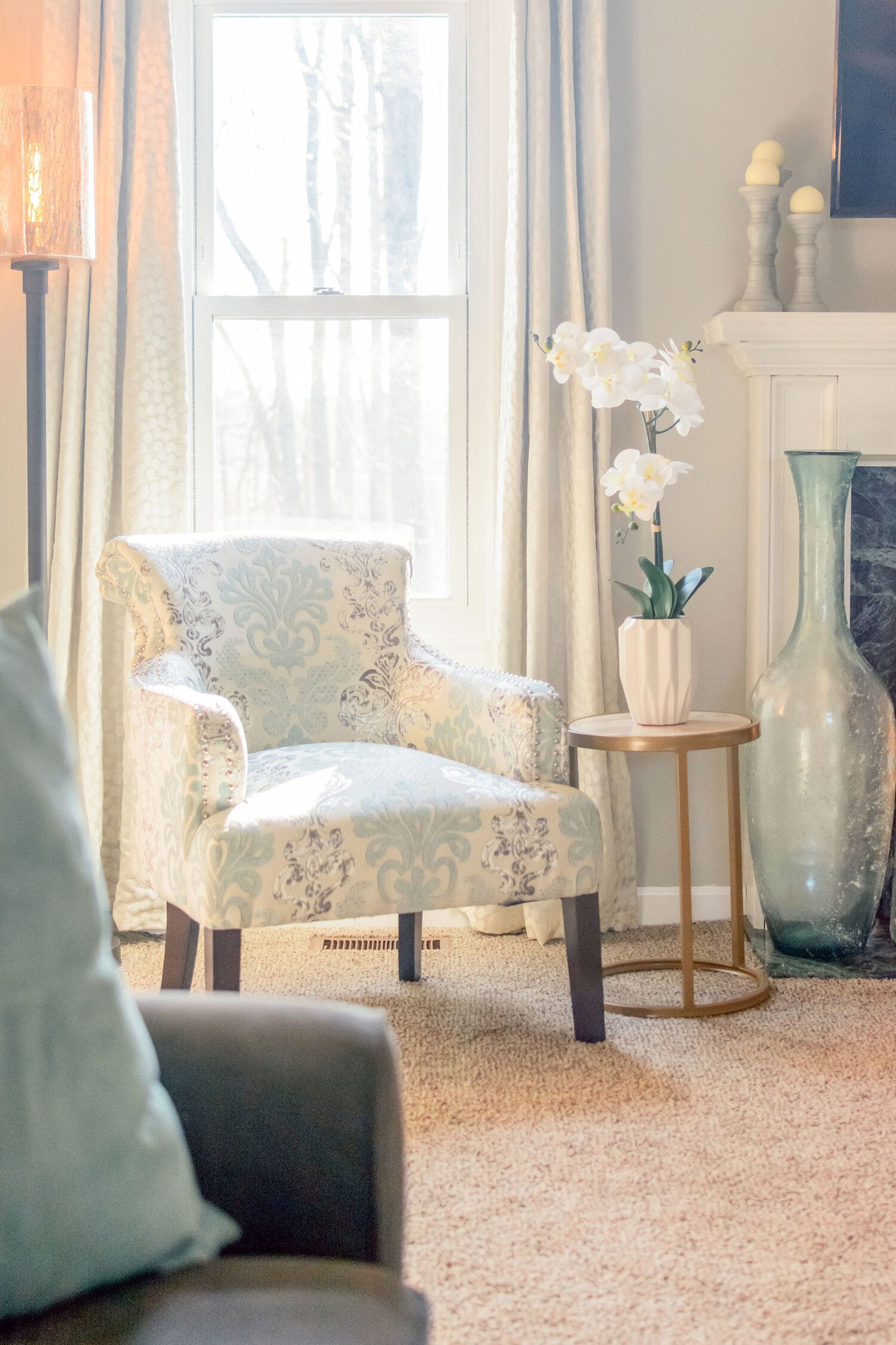A living room with a chair , couch , fireplace and vases.
