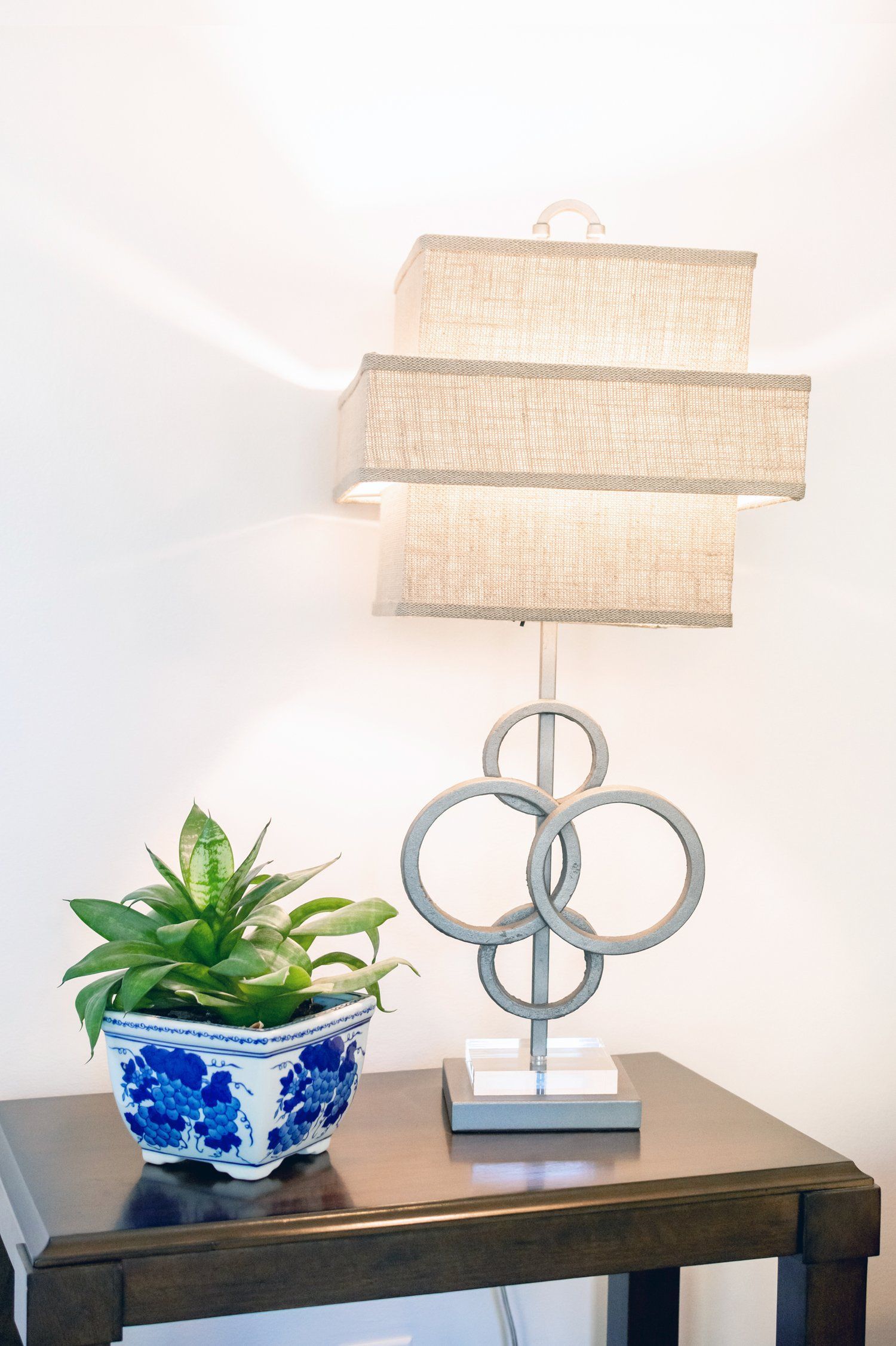 A lamp is sitting on a table next to a potted plant.