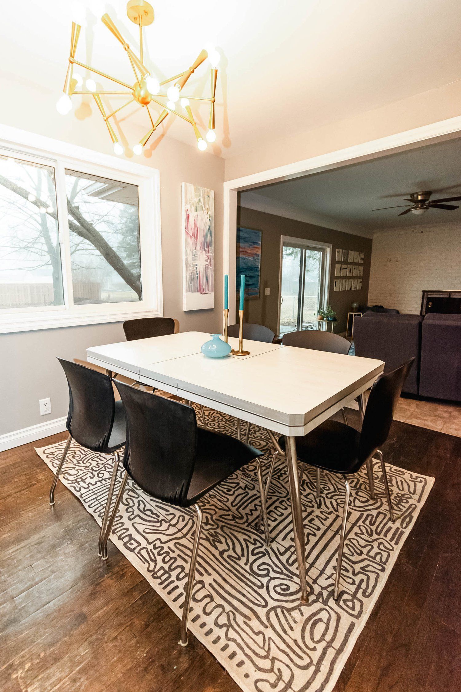 A dining room with a table and chairs and a rug.