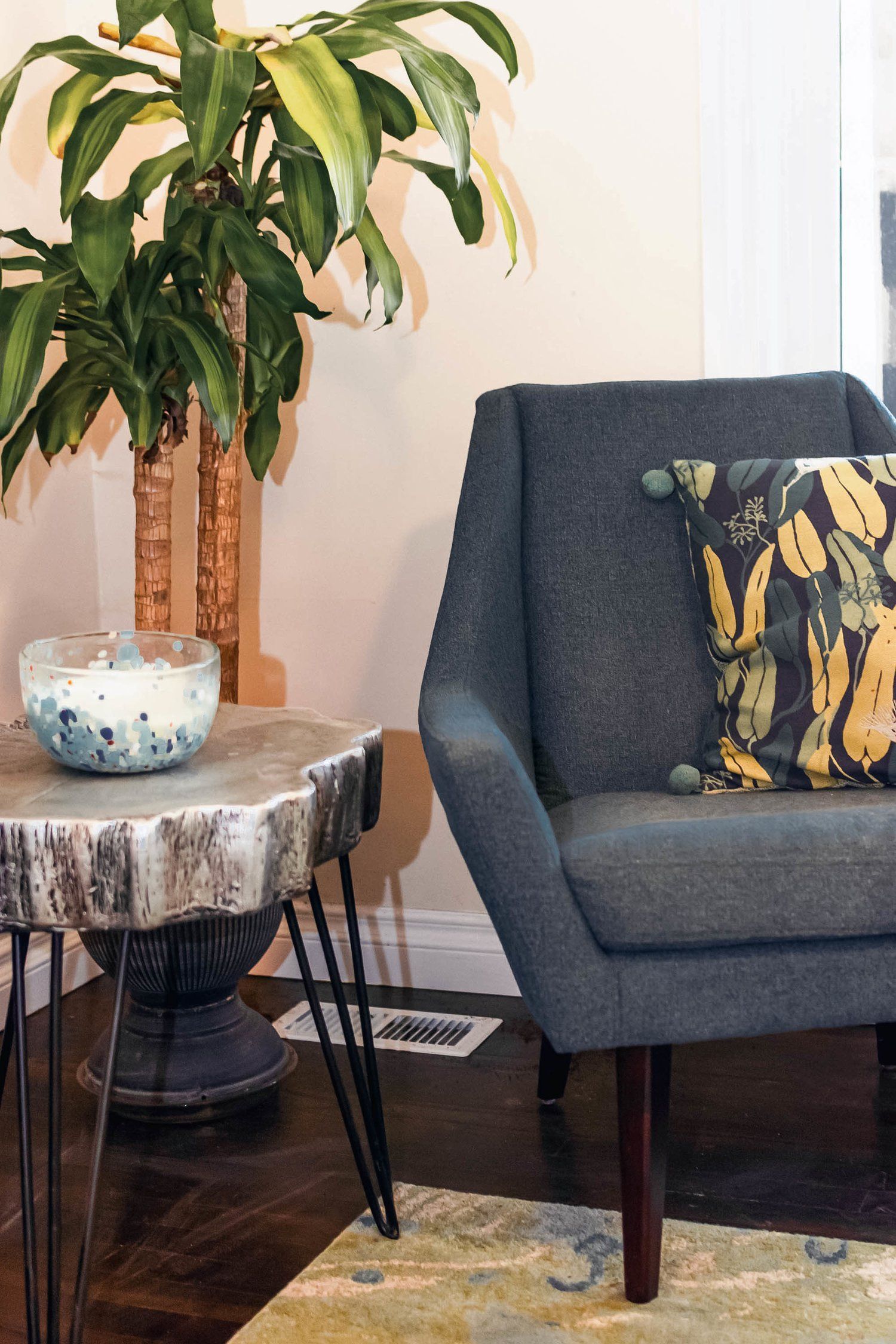 A chair and a table in a living room with a plant in the background.